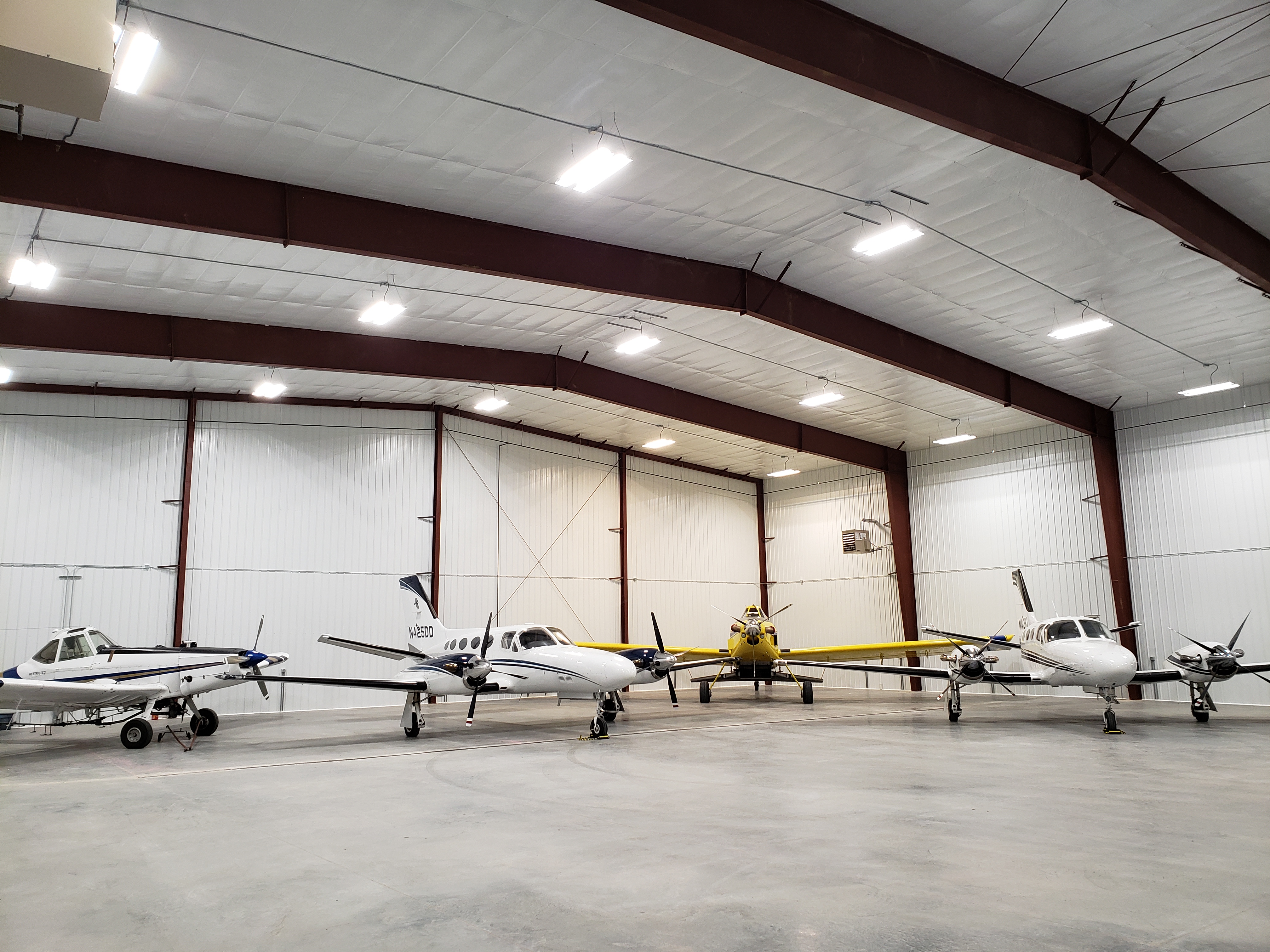 hangar with white planes and spray plane